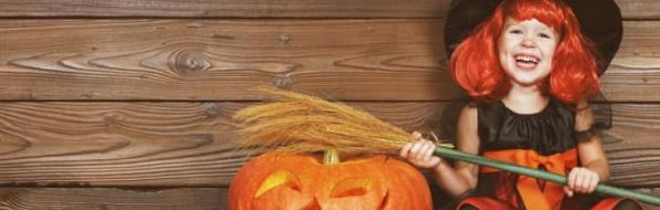 Girl dressed as a witch with a carved pumpkin and broom.